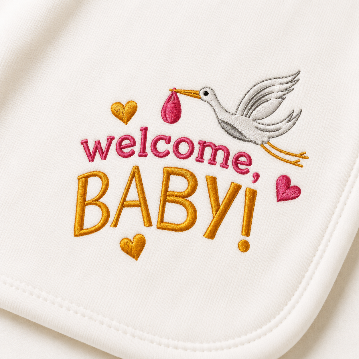 Close-up of the "Welcome, Baby!" stork embroidery detail on an organic baby blanket in pink and gold thread