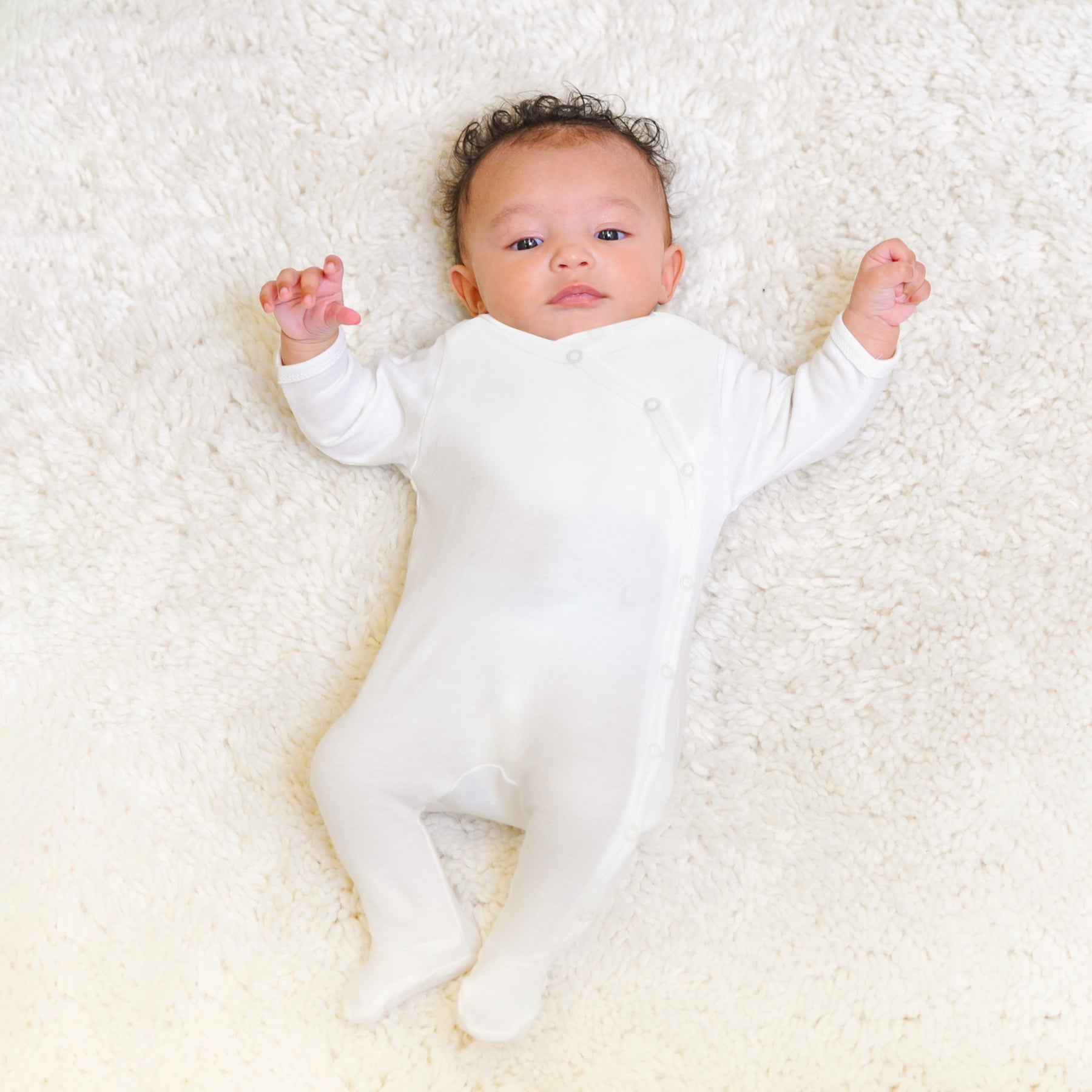 Newborn baby wearing Prima Cotton’s Organic Baby Sleepsuit for Sensitive Skin made from 100% GOTS-certified organic Egyptian cotton with a side snap fastening.