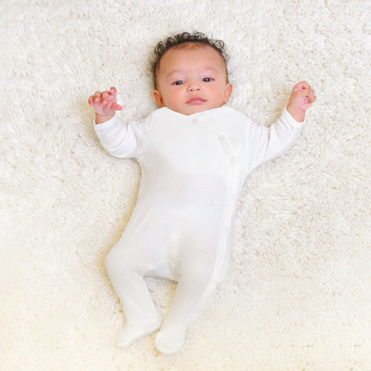 Newborn baby wearing Prima Cotton’s Organic Baby Sleepsuit for Sensitive Skin made from 100% GOTS-certified organic Egyptian cotton with a side snap fastening.